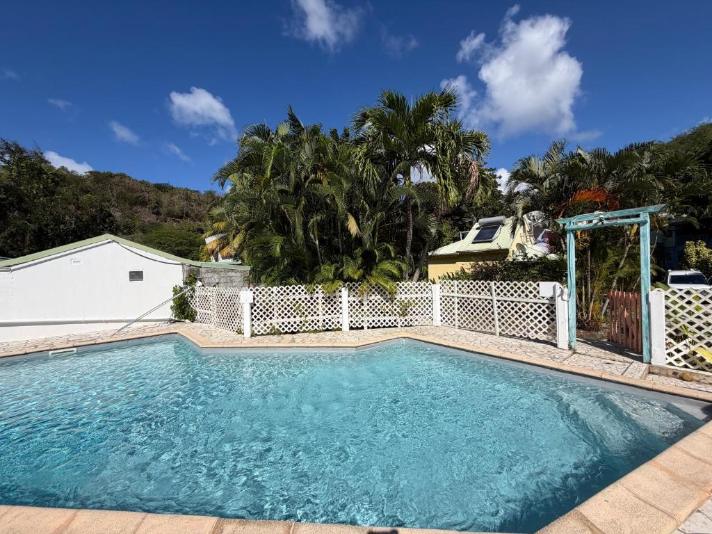 a swimming pool in front of a white fence at Résidence la Baie de Ti t Anse in Pointe-Noire