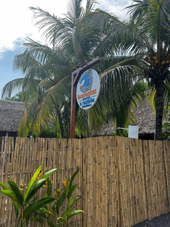 a sign over a wooden fence with palm trees at Backpackers Hostel in El Paredón Buena Vista