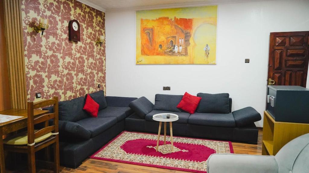 a living room with a blue couch and red pillows at Résidence Meublée Jihane in Laayoune