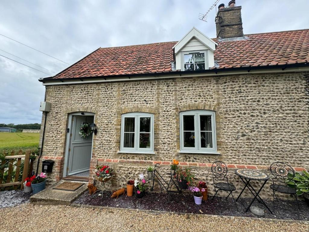 a brick house with a table and chairs in front of it at Cosy Flint Cottage in Thurston