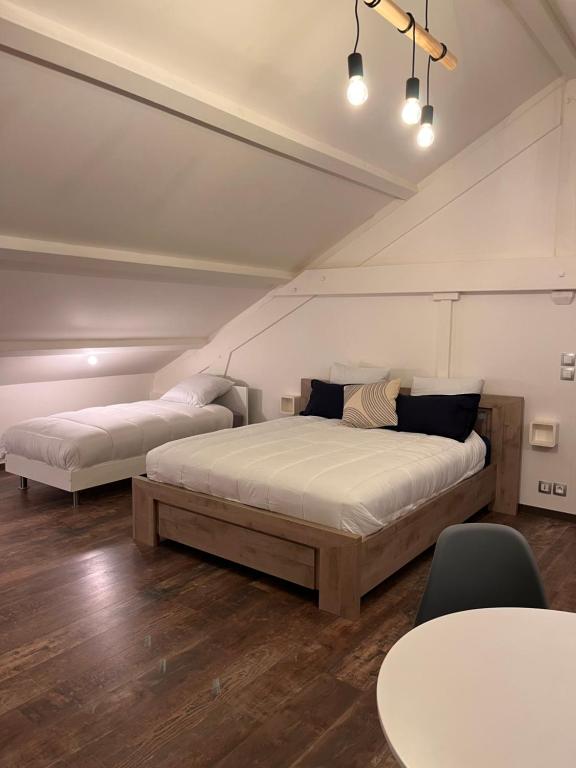 a bedroom with two beds and a table at L'escale Aéro Lyon in Saint-Laurent-de-Mure