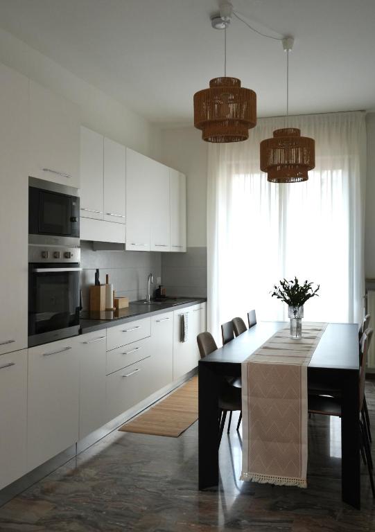 a kitchen with white cabinets and a table with chairs at UNIque Apt Bergamo 2 in Bergamo