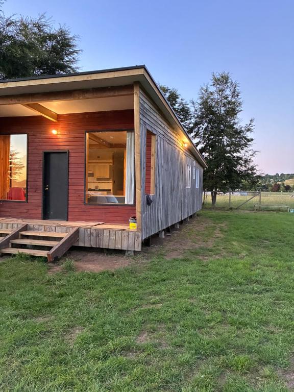 a small wooden house with a porch and a door at Cabaña de Lujo Independiente in Frutillar