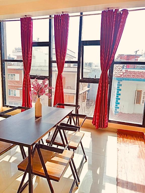 a dining room with red curtains and a table and chairs at The Himalayan Homes in Tokna
