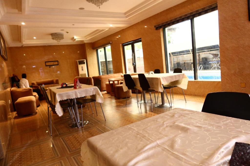 a restaurant with tables and chairs in a room at Vienna Suites in Owerri