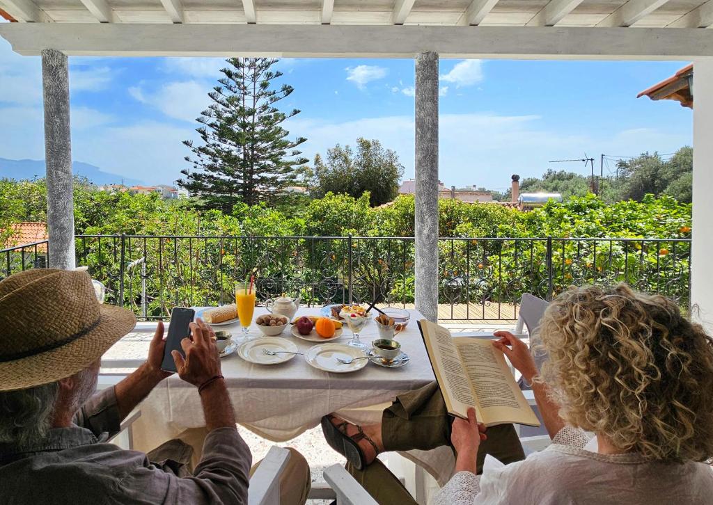 two people sitting at a table with food and a book at Orange Nest in Marathokampos