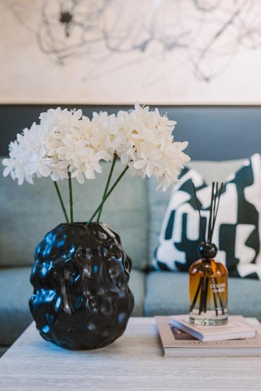 a black vase with white flowers on a table at SleepLuxury ApartHOUSE in Glasgow