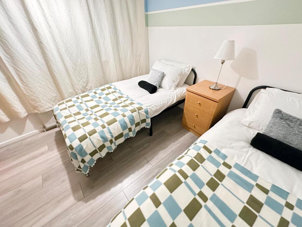 a bedroom with two beds and a lamp on a night stand at Luton Airport Accomodation in Luton