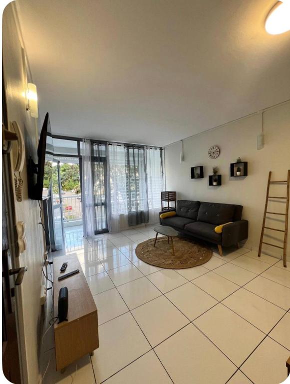 a living room with a black couch and a tv at Appartement 3 chambres récemment rénové in Les Abymes