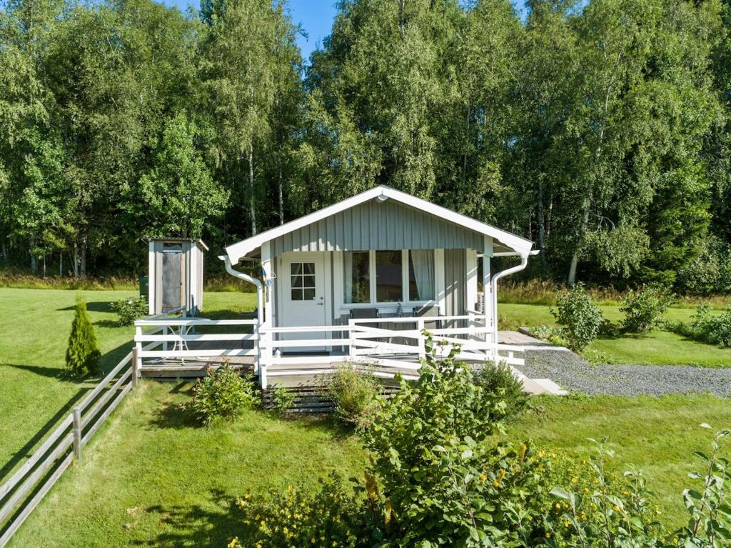 eine weiße Hütte auf einem Feld mit einem Zaun in der Unterkunft Calm in Nyland