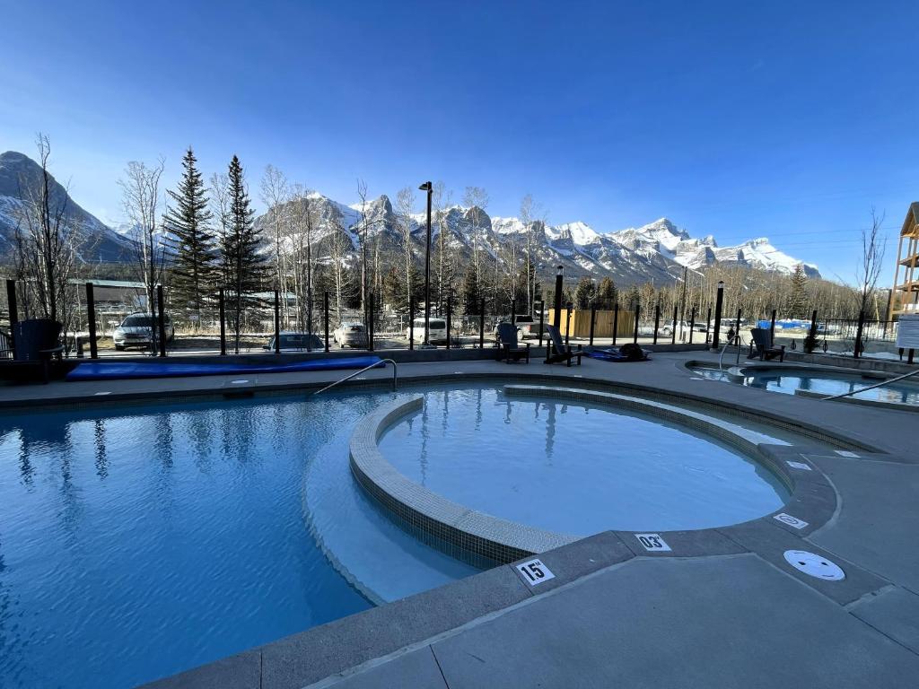 a large pool of water with mountains in the background at Black Bears Den, Heated Pool, Hot Tub, AC, brand new unit! in Canmore