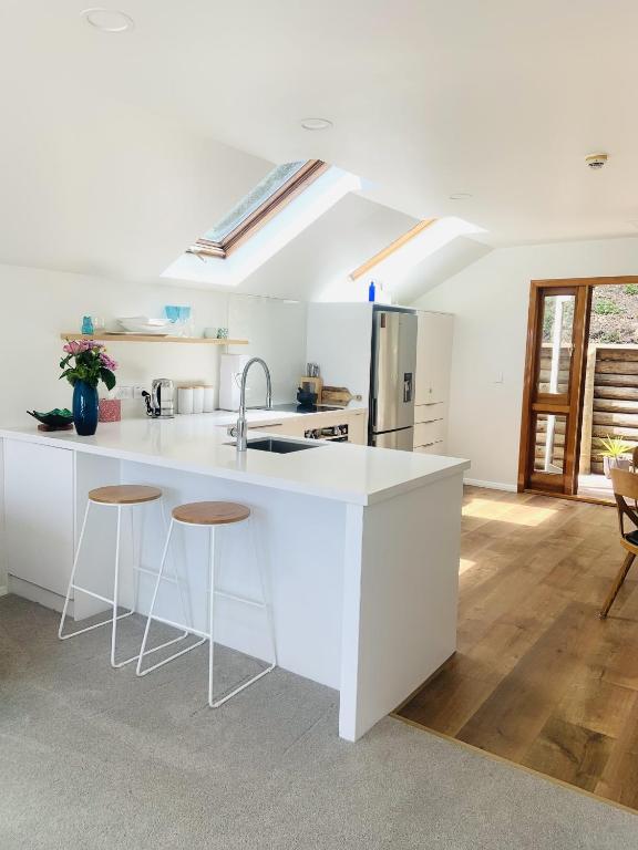 a white kitchen with a sink and stools at Nelson Harbour View in Nelson