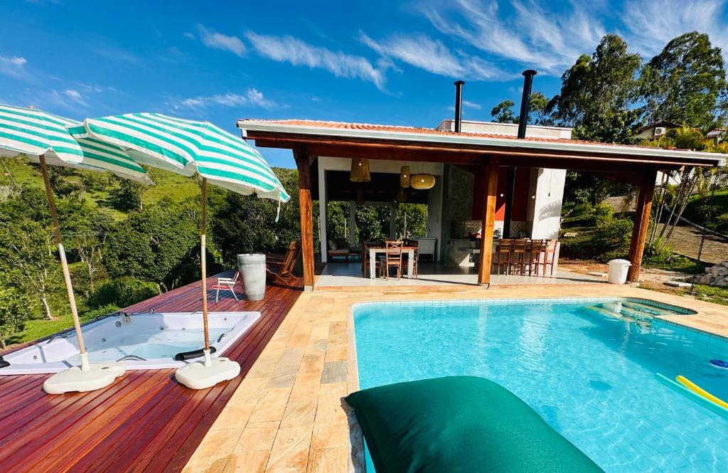 a swimming pool with umbrellas on a wooden deck at Sítio São Francisco da saudade Refugio Conforto e Afeto na Serra de Cunha a 200m do asfalto in Cunha