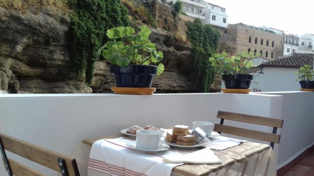 una mesa con un plato de comida en el balcón en Casa Bajo la Roca, en Setenil