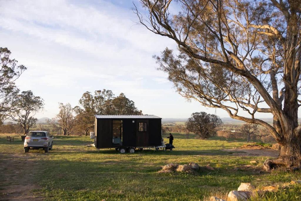 a tiny house parked in a field with a car at Beckford Tiny House 2 by Tiny Away in Good Hope