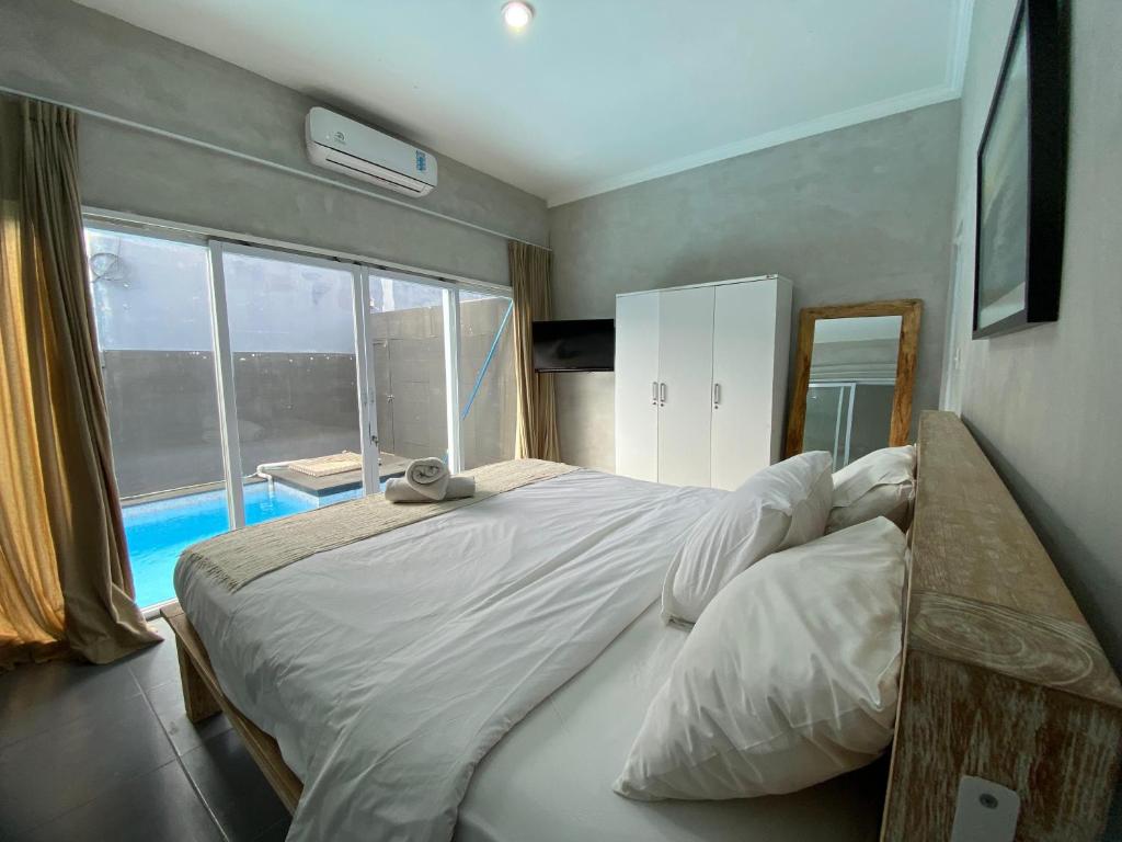 a bedroom with a large bed and a large window at Villa Kulat in Uluwatu
