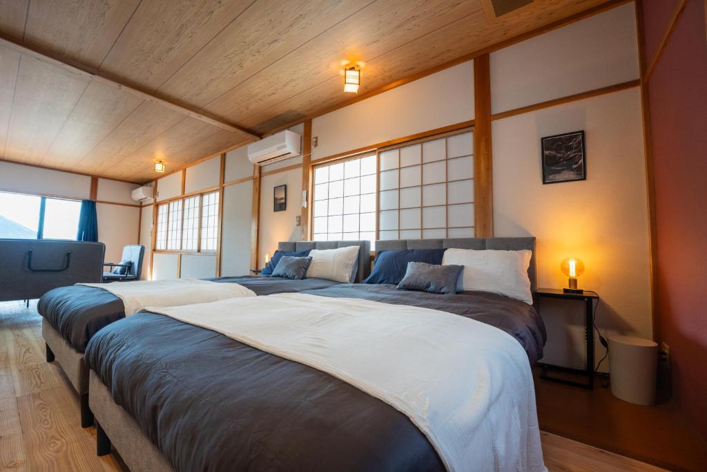 two beds in a room with two windows at Oceanfront Up to 14 Guests BBQ Available オーシャンフロント小浜田烏 in Obama