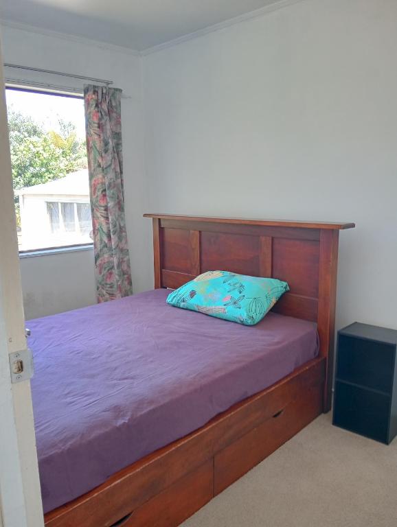 a bedroom with a wooden bed with a blue pillow at Papamoa budget accomodation's in Tauranga