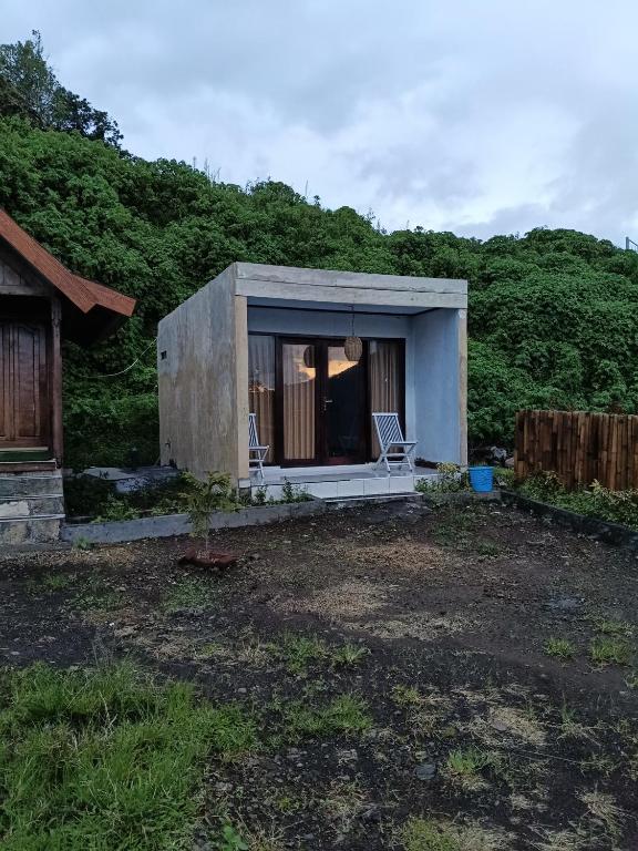 a small house with two chairs in a yard at Queen Rinjani Stay & Café in Sembalun Lawang