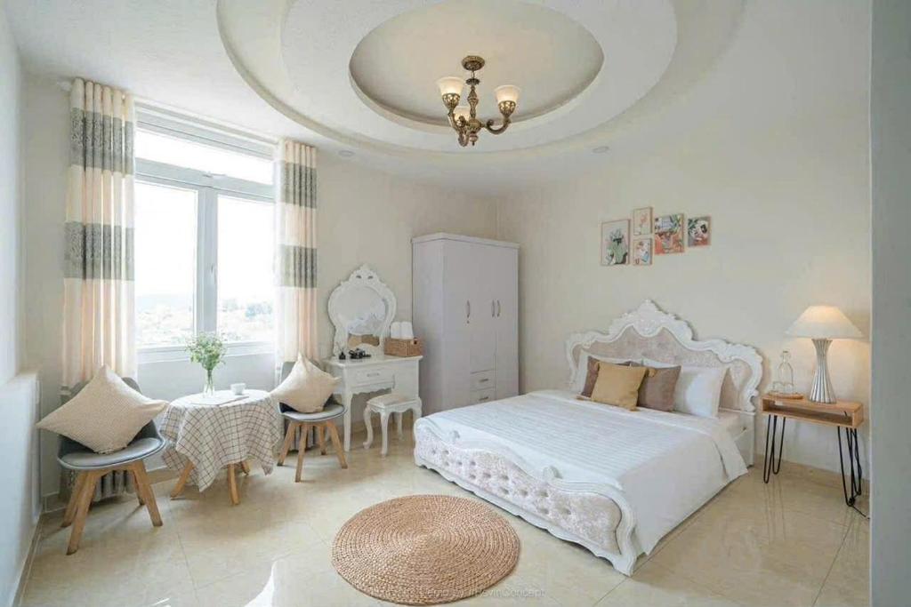 a bedroom with a white bed and a table and chairs at House Nguyễn in Da Lat