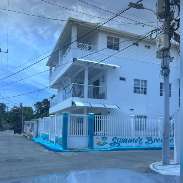 a white building with a blue fence in front of it at Summer Breeze in San Andrés