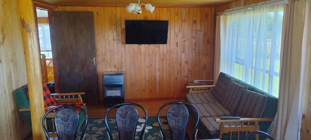 a living room with a couch and chairs and a television at Alojamiento Los Canelos in Ancud