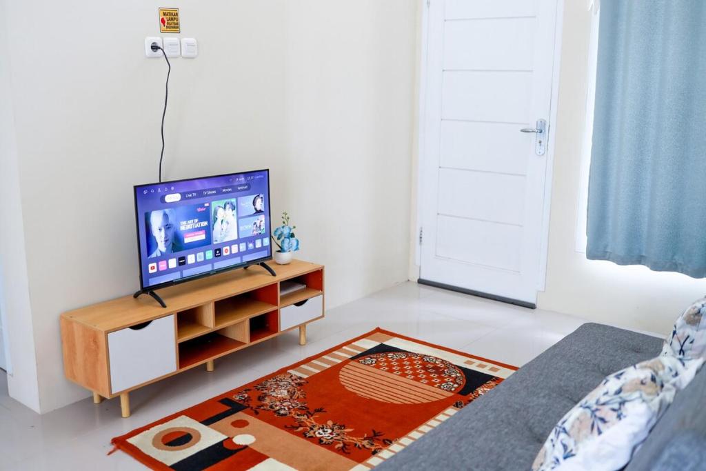 a living room with a tv on a stand at SYARIAH - 3BR Homeyy by Sakura in Krawang