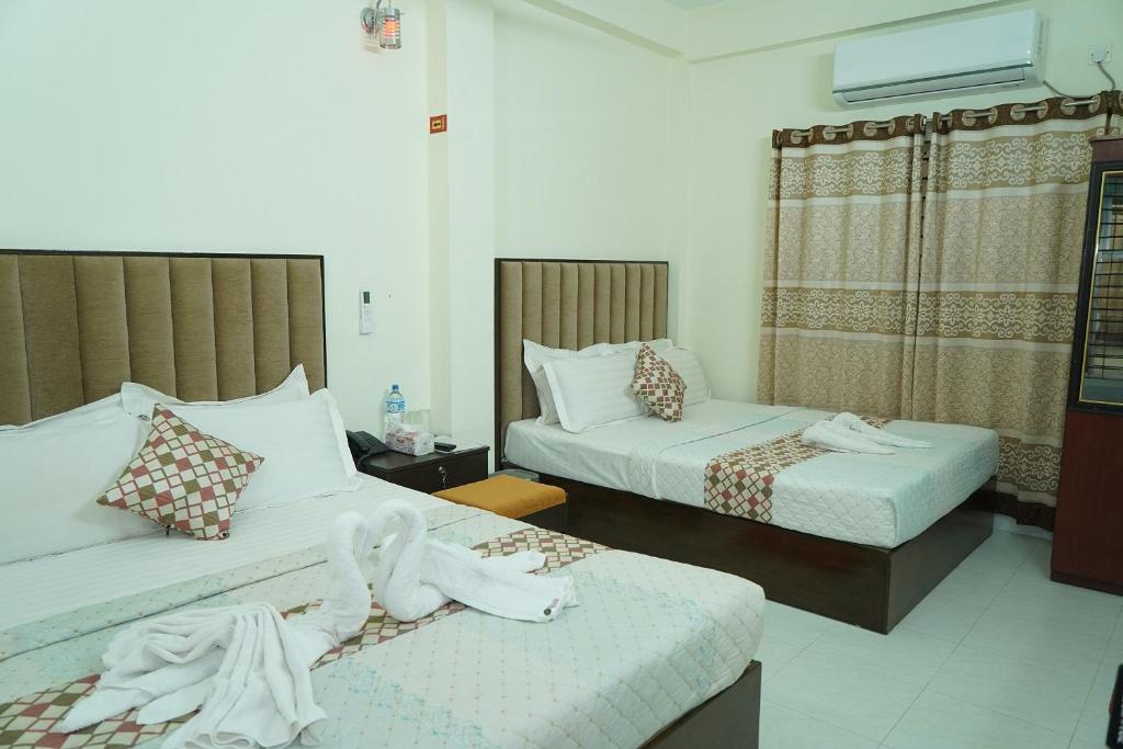 a hotel room with two beds with towels on them at Hotel Grand Shah Kamal in Sylhet