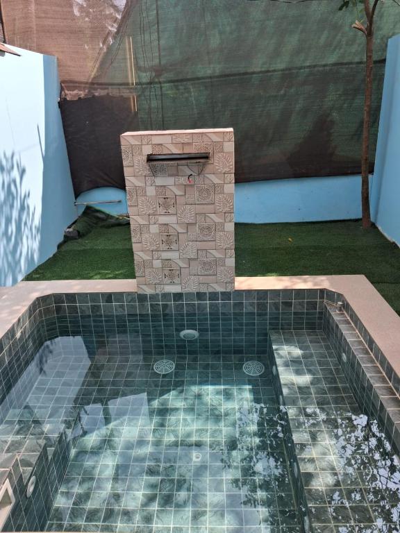 a small pool with a stone fireplace in a backyard at Sea Shades Cottages with Private Jacuzzi in Palolem