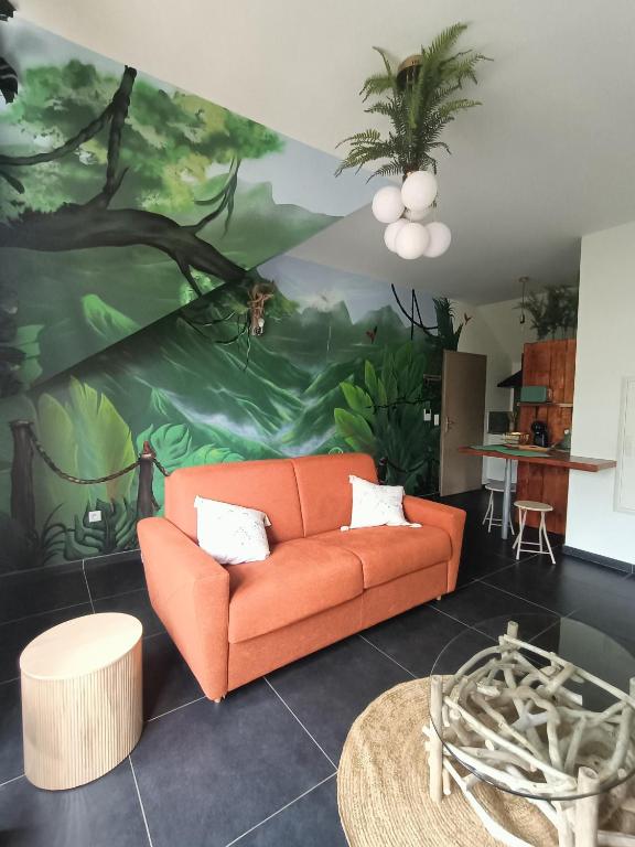 an orange couch in a living room with a painting at La Cabane du lagon atypique et accès à la plage in La Saline les Bains