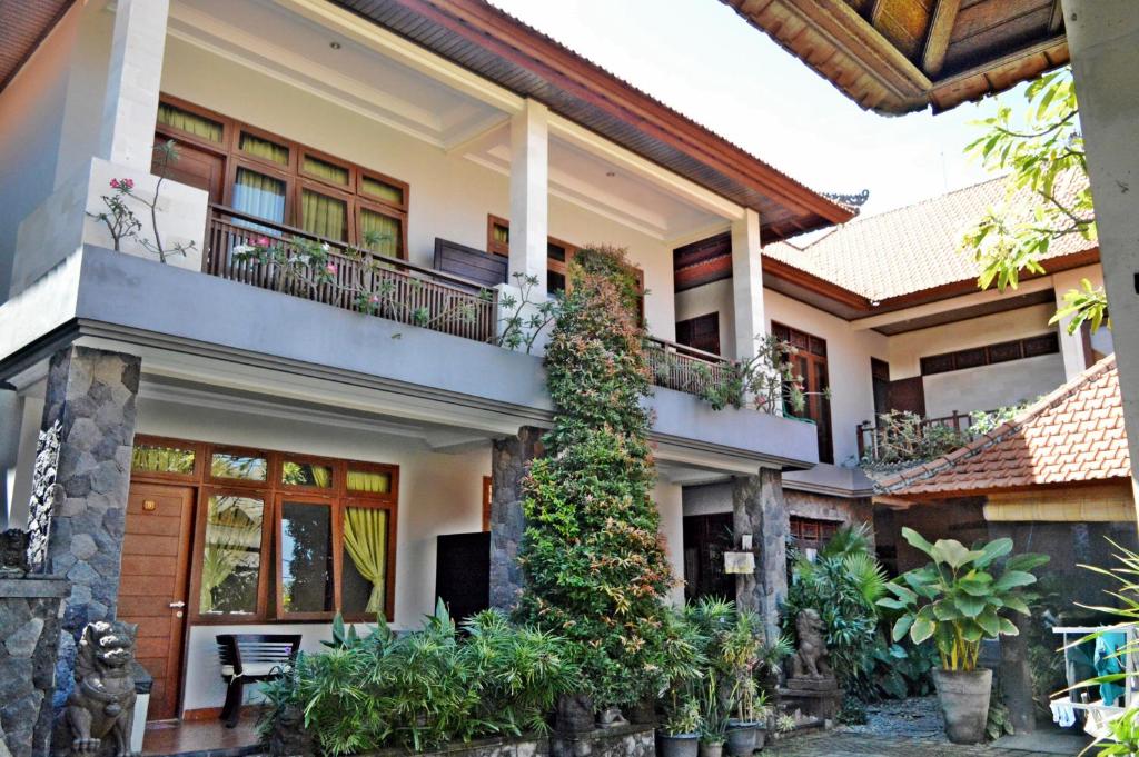 a house with a balcony and plants at Yulia 2 Homestay Sanur in Sanur