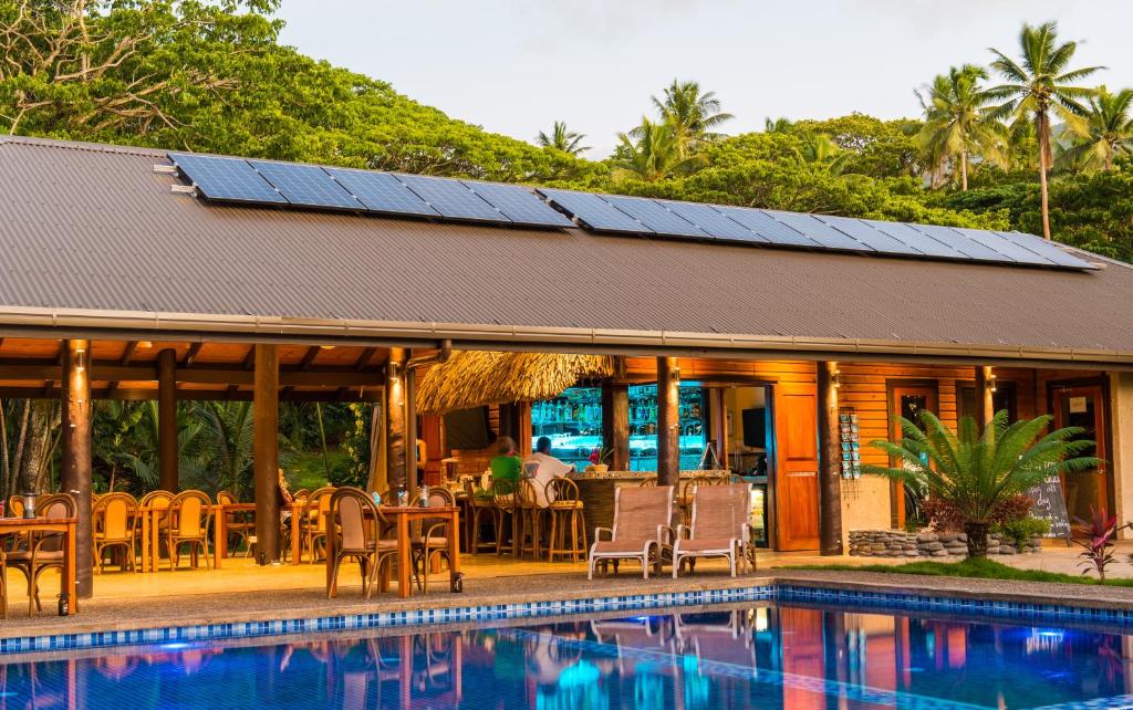 Waiyevo的住宿－塔妙妮潛水度假酒店，一座带游泳池的房子和一座带太阳能电池板的房子