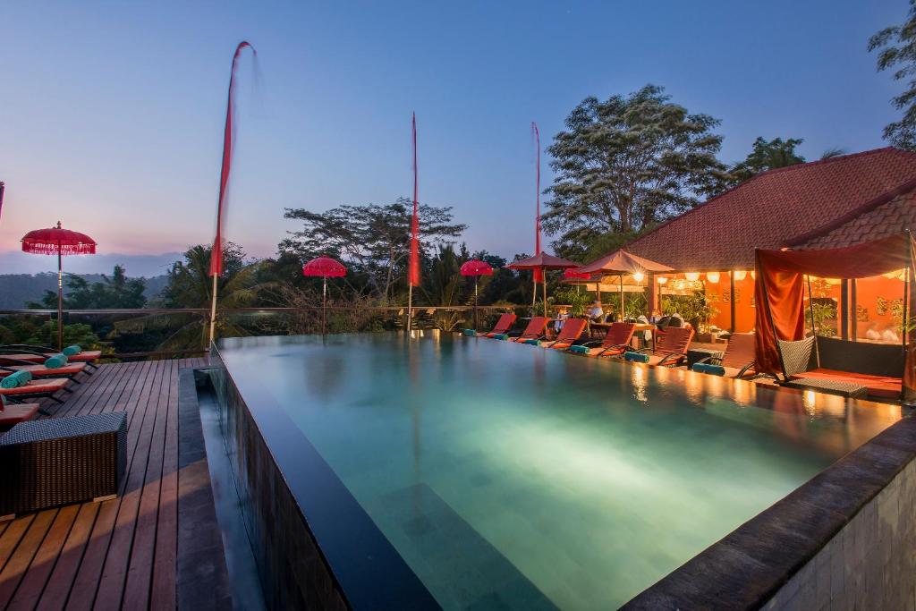 a swimming pool with chairs and umbrellas at night at Jungle Retreat by Kupu Kupu Barong in Ubud