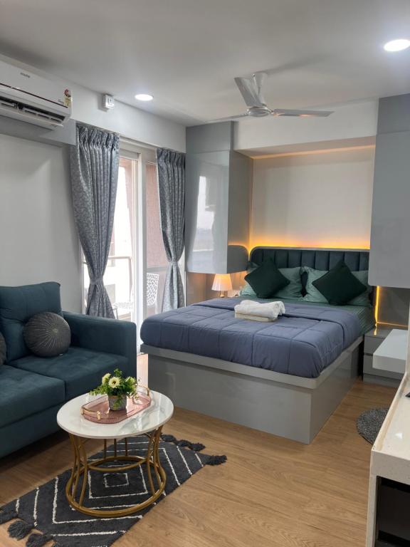 a bedroom with a bed and a couch and a table at NEON - Nirvana Stays With PVT Balcony -1 Km from Airport in Pune