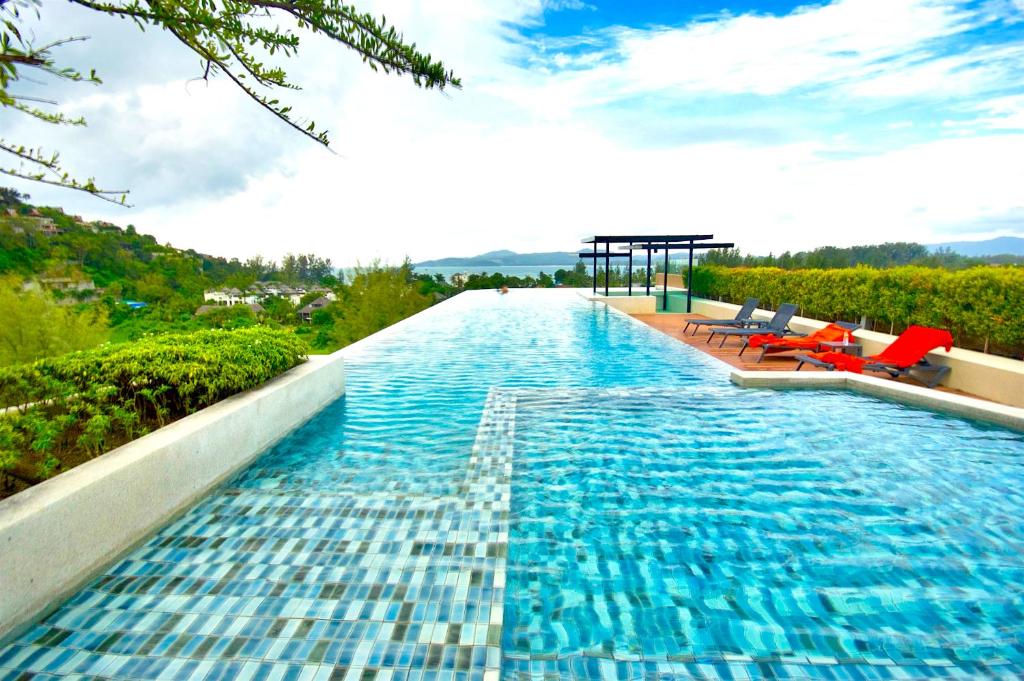 - une piscine d'eau bleue et de chaises rouges dans l'établissement 6th Avenue Surin by Risa, à Surin Beach