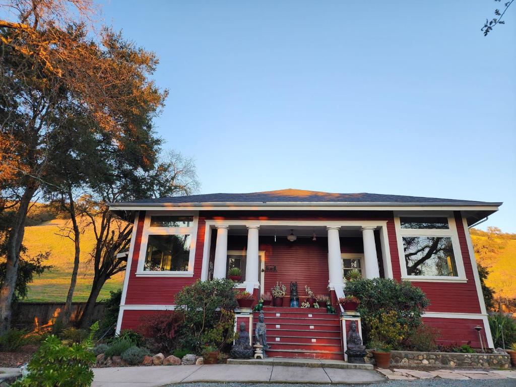 a red house with a red door and columns at Amitabha Wine Country Cottage in Santa Rosa