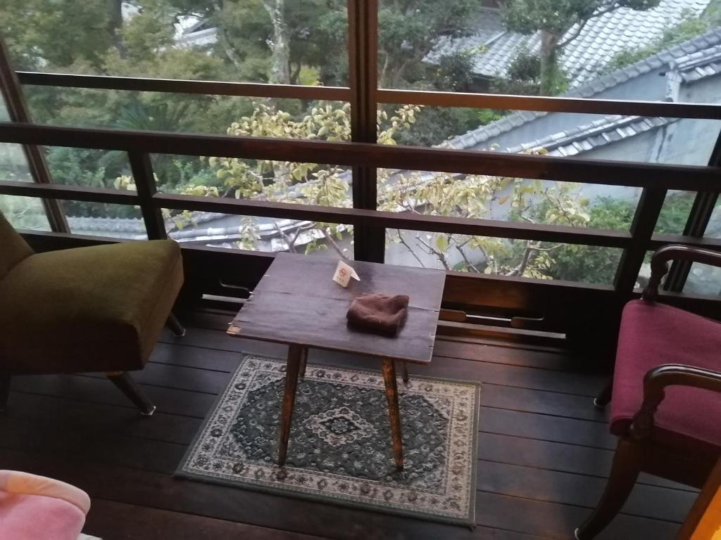a small table on a balcony with a window at z Authentic Trad Villa experience in Onomichi
