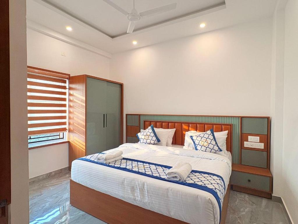 a bedroom with a large bed with blue and white pillows at Pullat Suites in Kalpetta