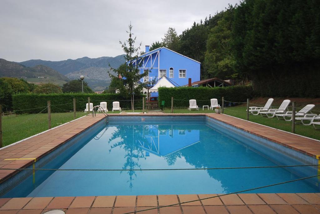 a swimming pool with chairs and a blue house at Vega Del Sella in Arriondas