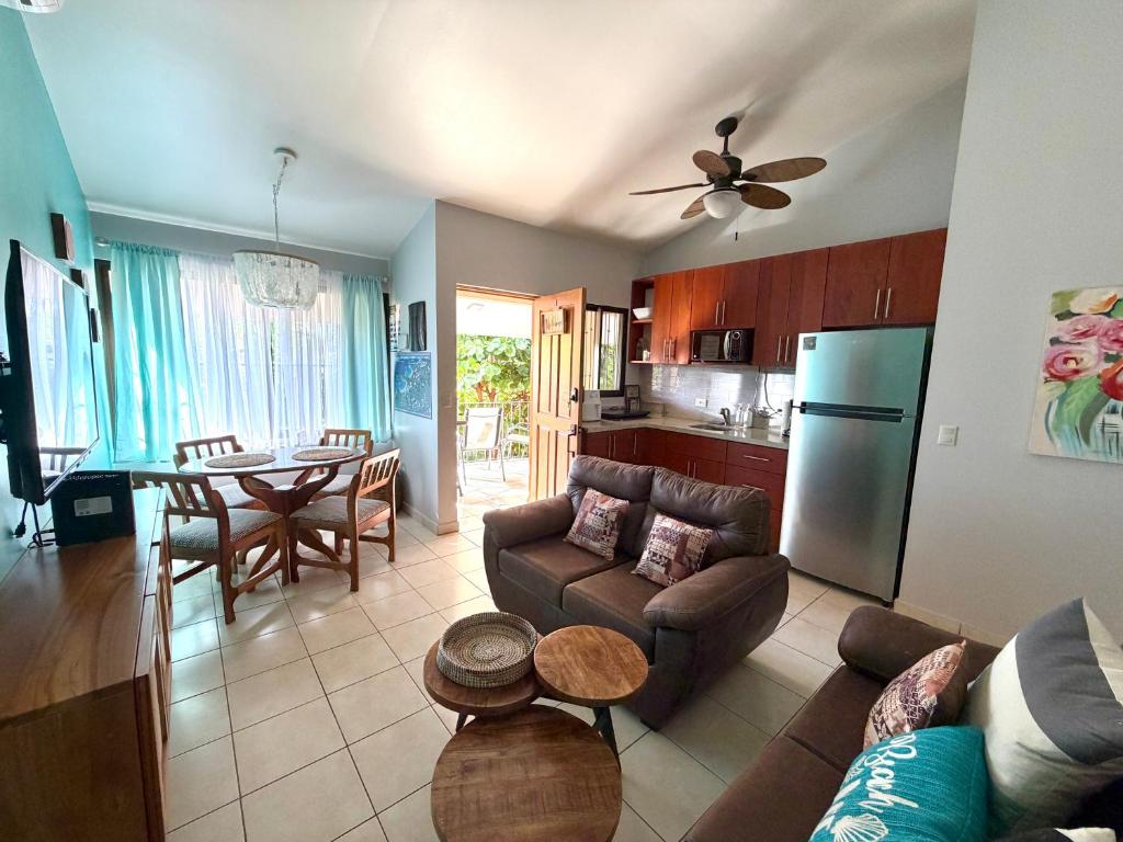 a living room with a couch and a table and a kitchen at Happy Oasis Second Floor Condo with Terrace in Coco