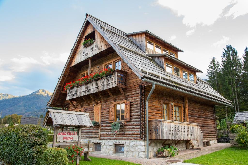 a log house with flowers on the balcony at Apartments Brina in Bohinj