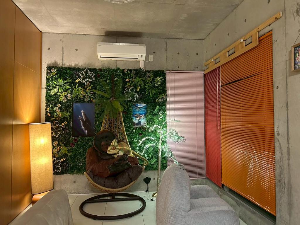 a room with two chairs and a wall with plants at オランウータンApple House Ginowan in Ginowan