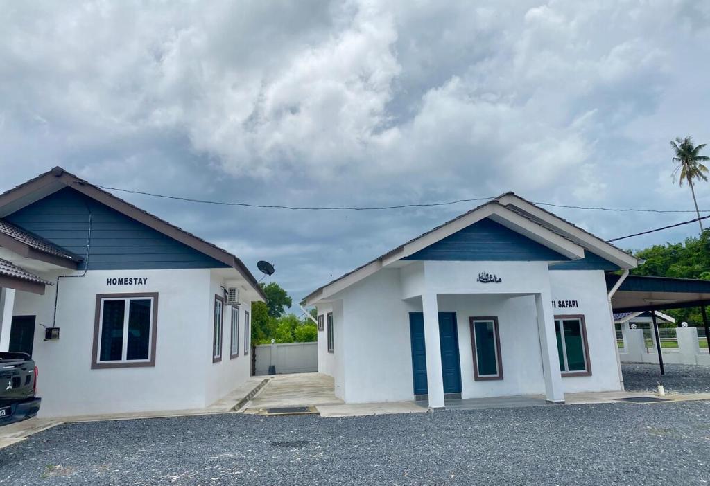 a white and blue house with a parking lot at Homestay Babah in Jitra