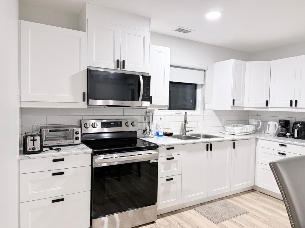 a kitchen with white cabinets and a black stove top oven at Private 1BR Suite with Kitchen, Laundry, Parking & 1 Gigabit Internet in Whitehorse