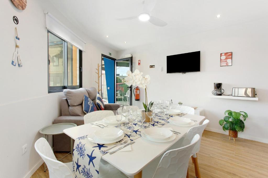a white dining room with a white table and chairs at O Marinheiro 15B in Machico