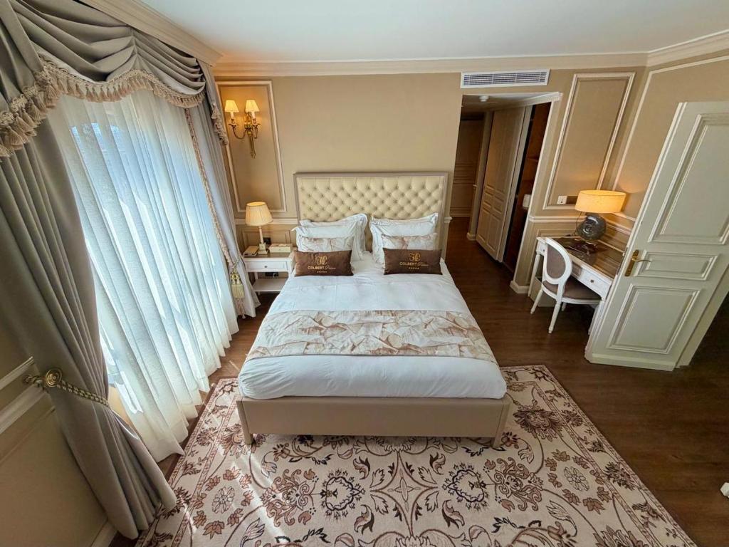 a bedroom with a bed and a large window at Hôtel Colbert Palace in Antananarivo