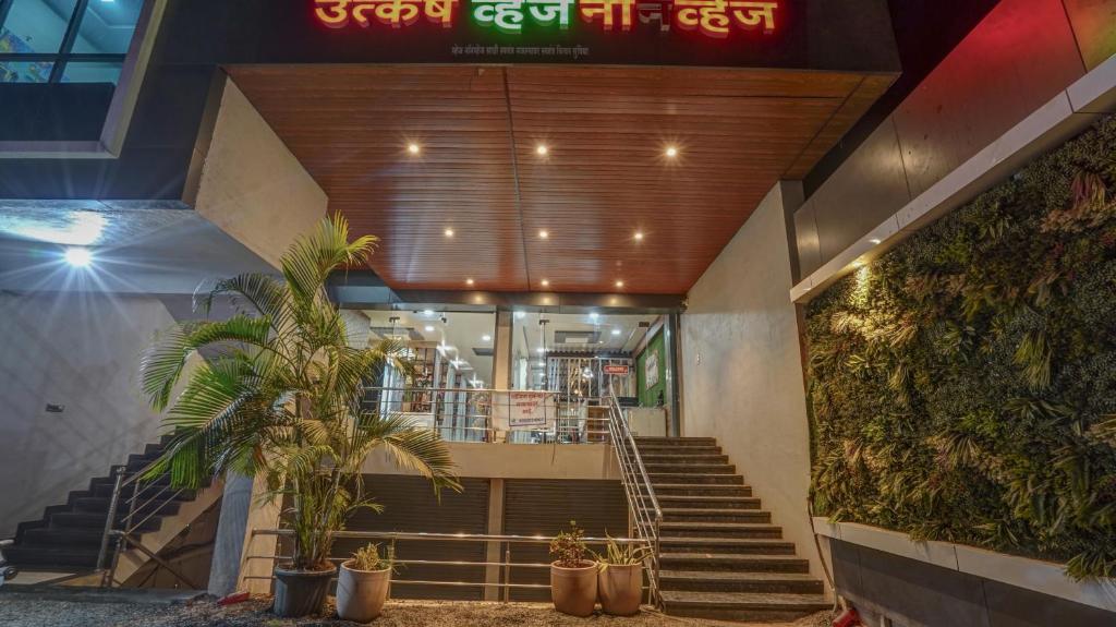a lobby of a building with stairs and plants at Utkarsh Hotel & Lodging in Jāmkhed