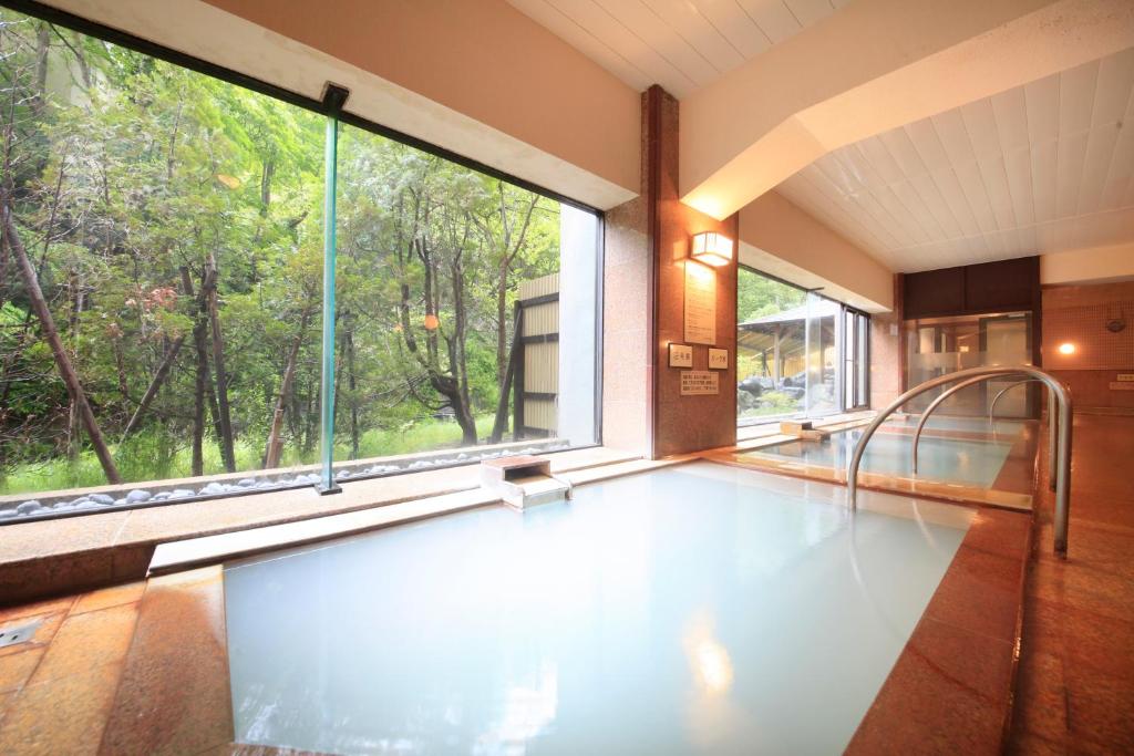 a swimming pool in a room with a large window at Park Hotel Miyabitei in Noboribetsu