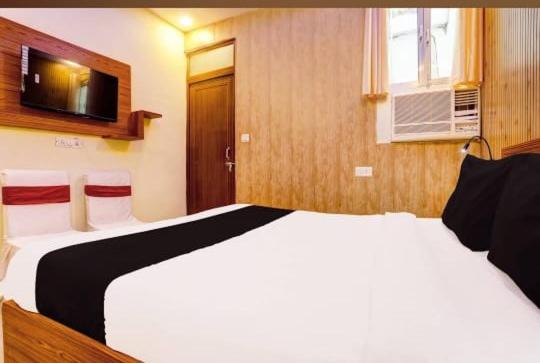a bedroom with a large white bed and a television at RROOMS Eco Hotel Blue Stone- Near Singapore Mall And Max Hospital in Lucknow