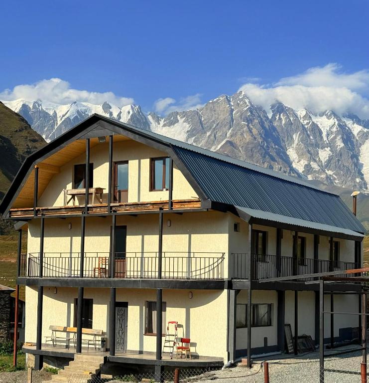 a large house with mountains in the background at Guesthouse Angelina in Ushguli